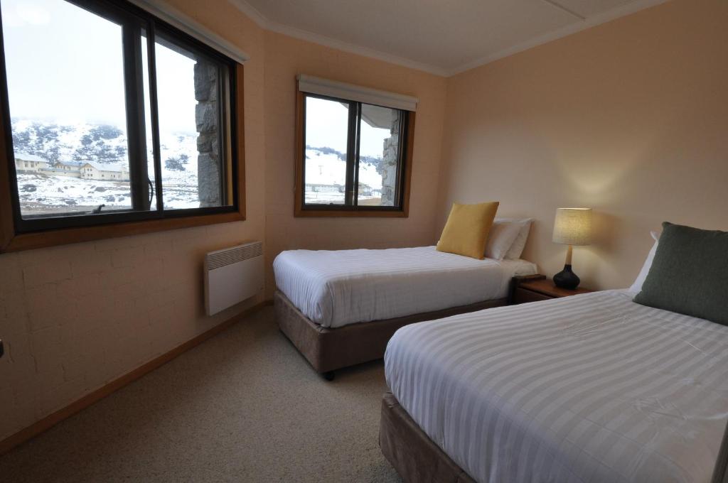 a hotel room with two beds and two windows at Salzburg Apartments in Perisher Valley
