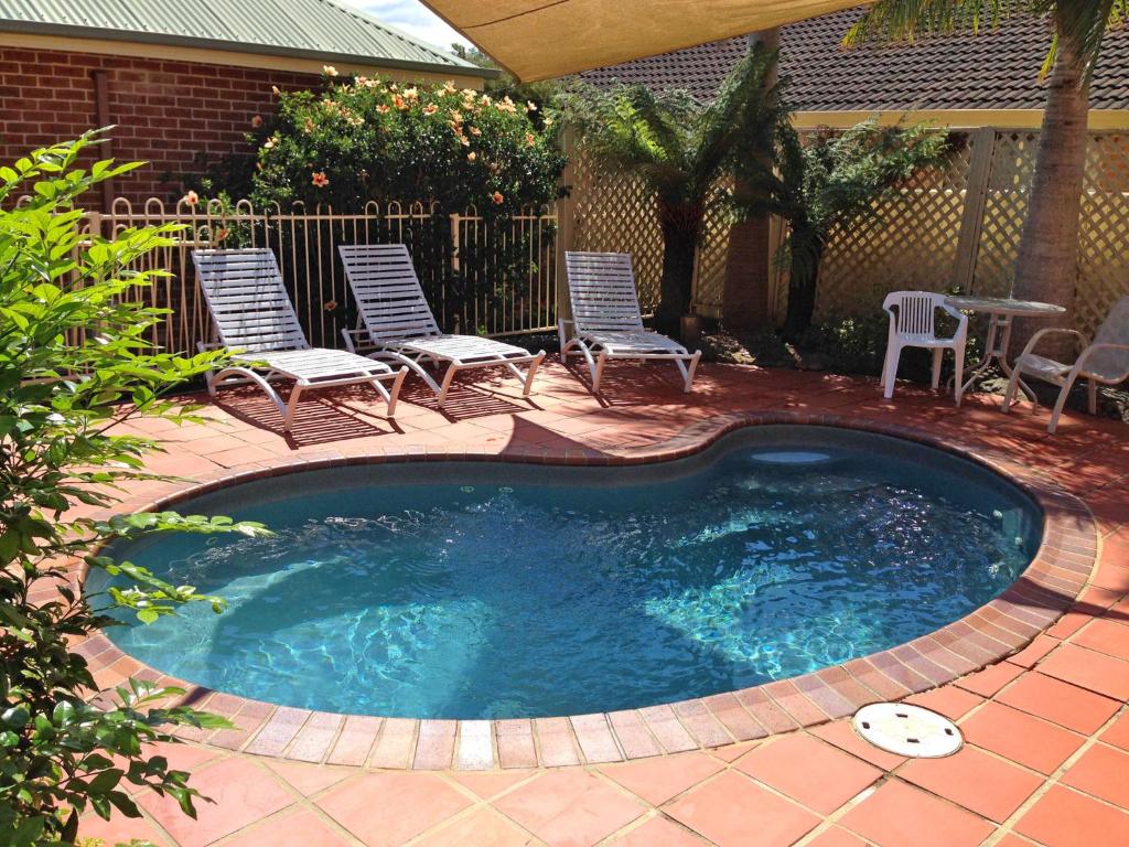 a small swimming pool with chairs and a table at Dolphin Shores in Vincentia