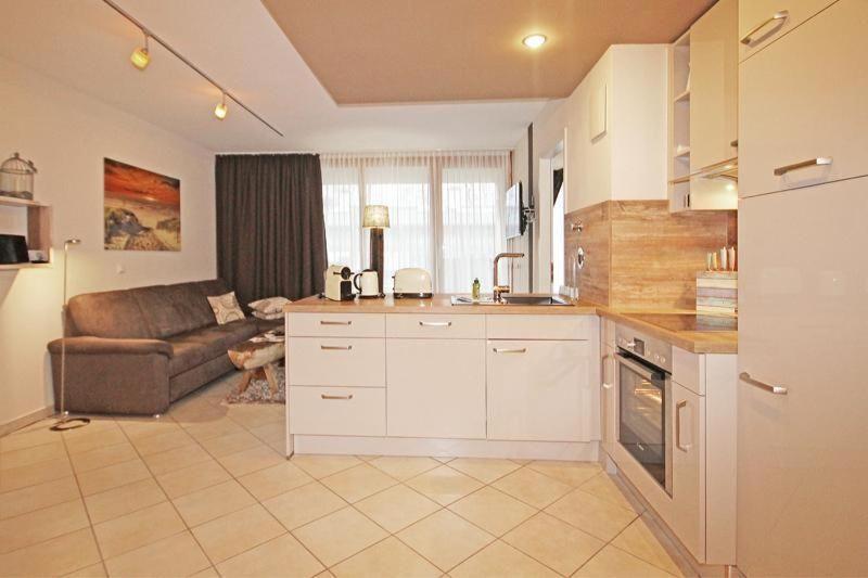 キュールングスボルンにあるHaus-Mecklenburg-Wohnung-15-9500の白いキャビネットとソファ付きのキッチンが備わります。