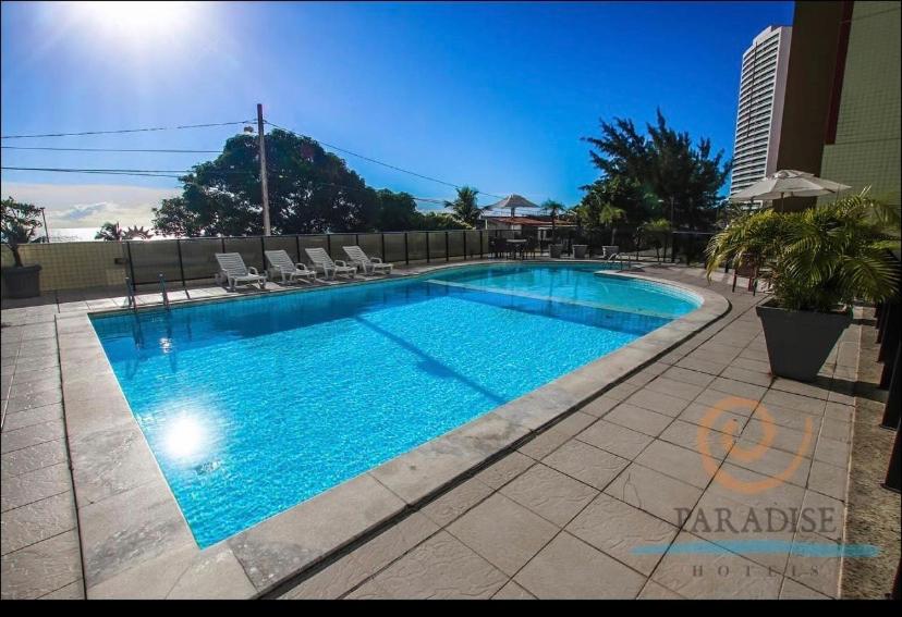 uma grande piscina azul com cadeiras e um edifício em Apartamento Ponta Negra em Natal