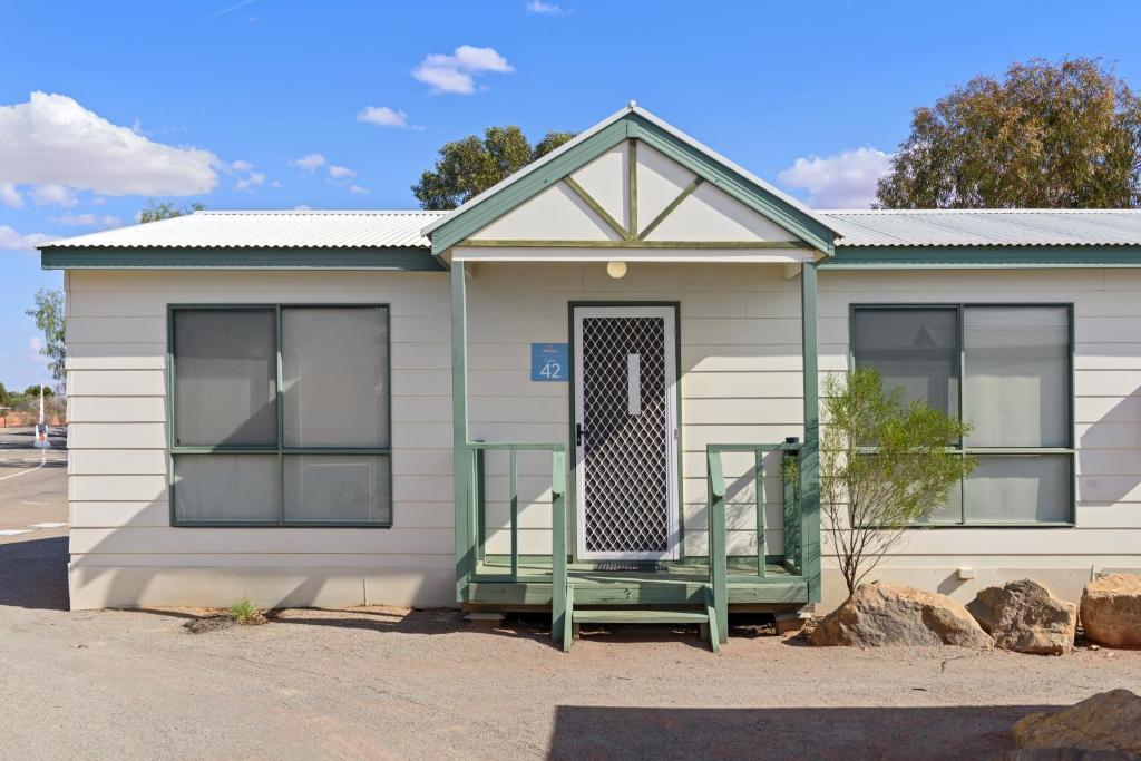 a small white house with a green door at Discovery Parks - Roxby Downs in Roxby Downs