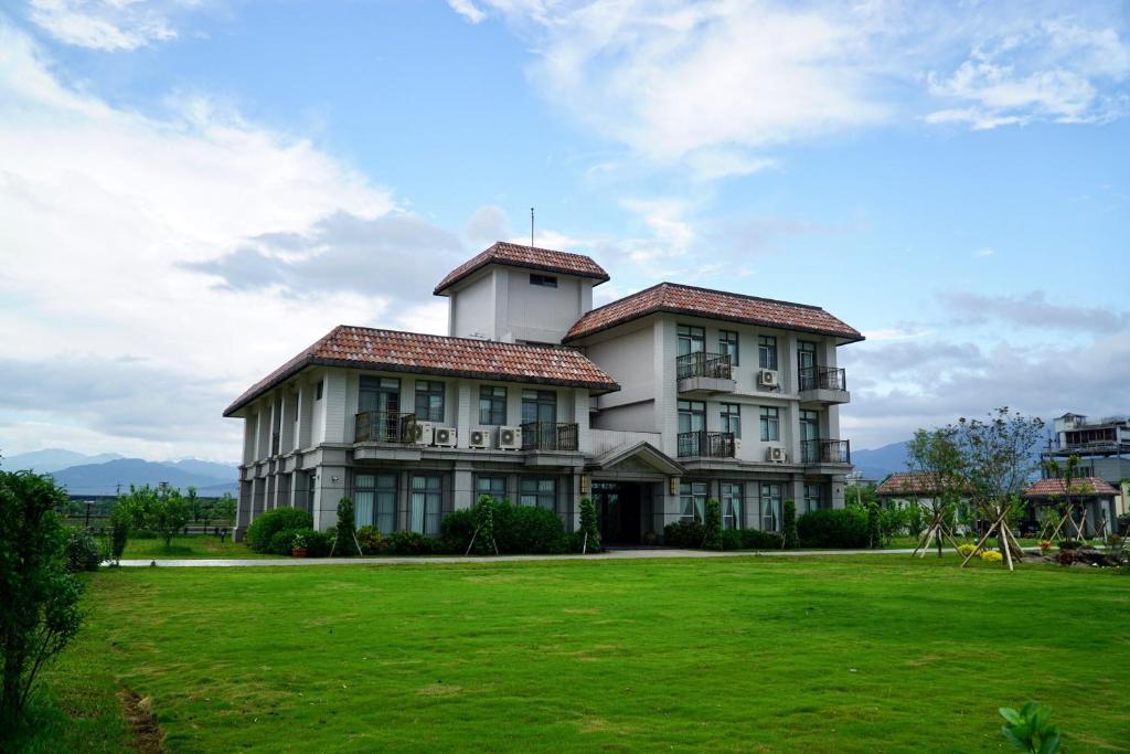 una casa grande con un campo verde delante de ella en Dafu Qiandai Manor, en Zhuangwei