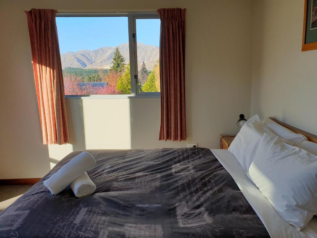 a bedroom with a large bed with a large window at Aorangi House in Lake Tekapo