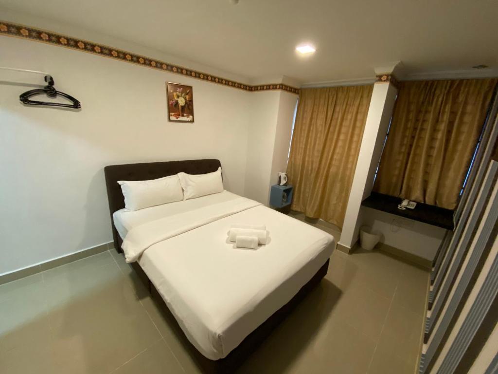 - une chambre avec un grand lit blanc et une serviette dans l'établissement Shobi Hotel Johor Bahru Near CIQ JB, à Johor Bahru