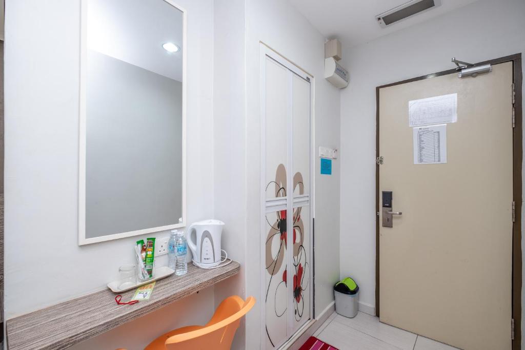 a room with a white wall with a desk and a mirror at BG Business Hotel in Bukit Mertajam