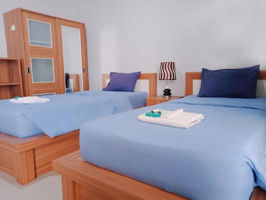 2 bedden in een slaapkamer met blauwe lakens en handdoeken bij Prada Apartment in Seminyak