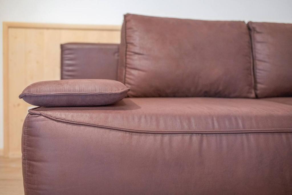 Un sofá de cuero marrón con dos almohadas. en Residence krUma, en Valdaora