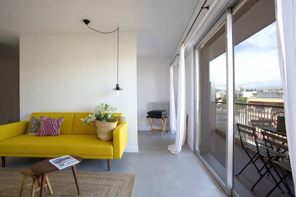 d'un salon avec un canapé jaune et un balcon. dans l'établissement Appartement près des plages, à Antibes