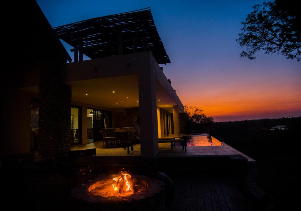 a fire pit in front of a house at sunset at Manzini River House in Hectorspruit