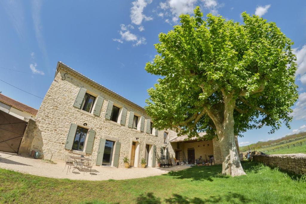 una casa de piedra con un árbol delante en Domaine de Sévanes, en Saint-Paul-les-Fonts