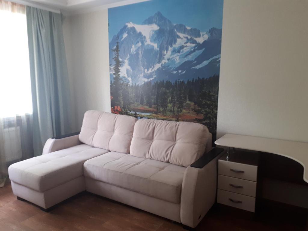 un sofá blanco en la sala de estar con un mural de montaña en 2 комн. 5 мест, 10 мин. до Центра en Kirovograd