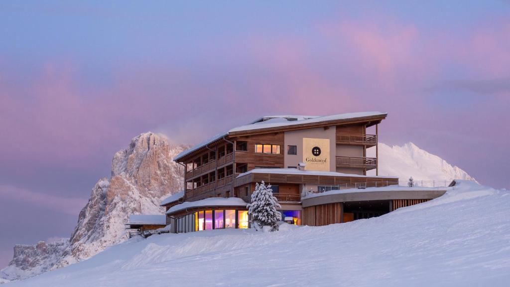 ein Gebäude auf einem schneebedeckten Berg in der Unterkunft Hotel Goldknopf in Alpe di Siusi