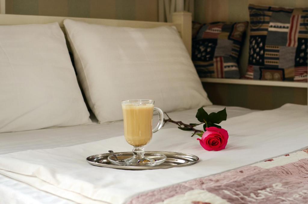 a glass of orange juice on a bed with a rose at Panska Poduszka in Lviv