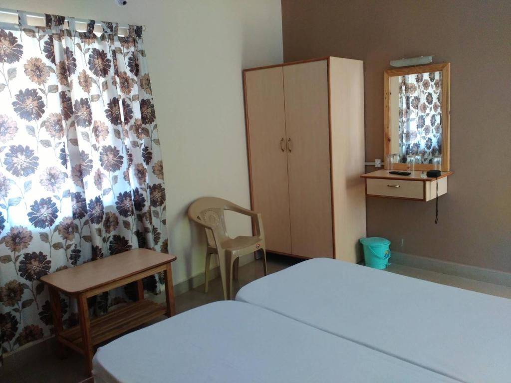 een slaapkamer met een bed, een stoel en een kast bij HOTEL RUKMINI in Vasco Da Gama