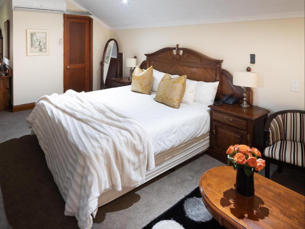 a bedroom with a large white bed and a table at Gallo Manor Executive Bed & Breakfast in Johannesburg