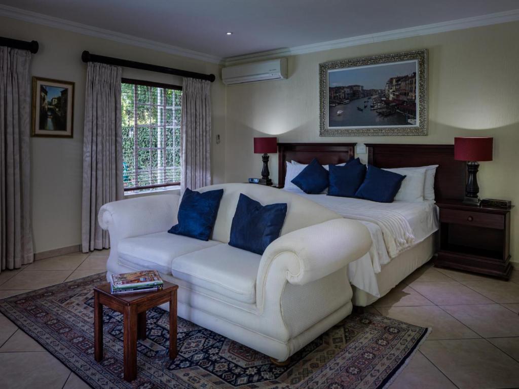 a bedroom with a white bed and a couch at Gallo Manor Executive Bed & Breakfast in Johannesburg