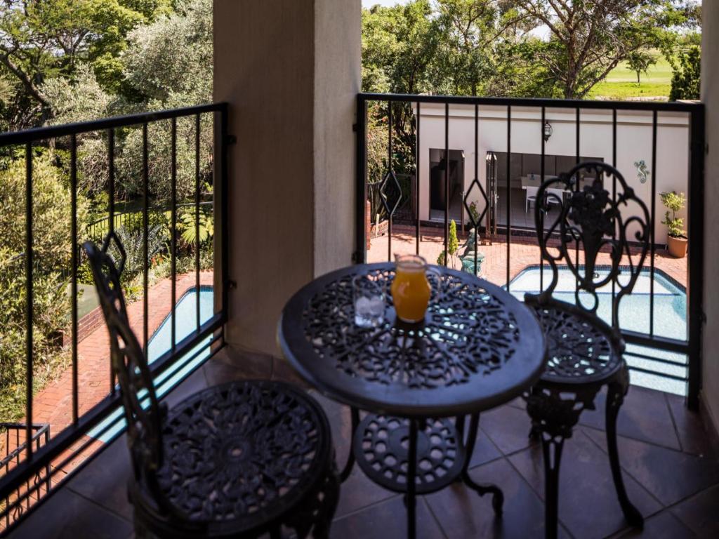a table and chairs on a balcony with a view of a pool at Gallo Manor Executive Bed & Breakfast in Johannesburg