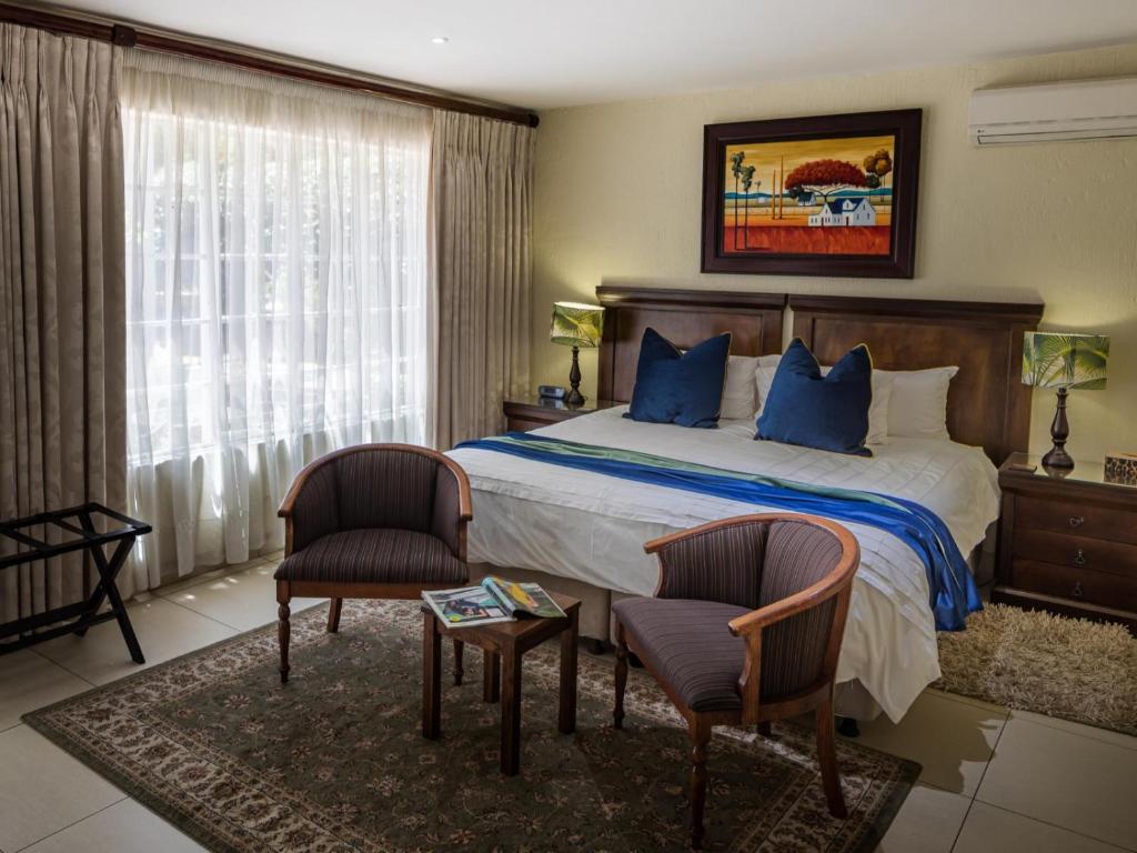 a hotel room with a bed and two chairs at Gallo Manor Executive Bed & Breakfast in Johannesburg