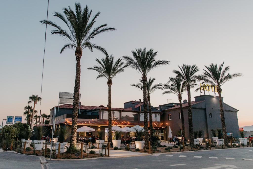 a hotel with palm trees in front of a building at Hotelet elRetiro in Cambrils