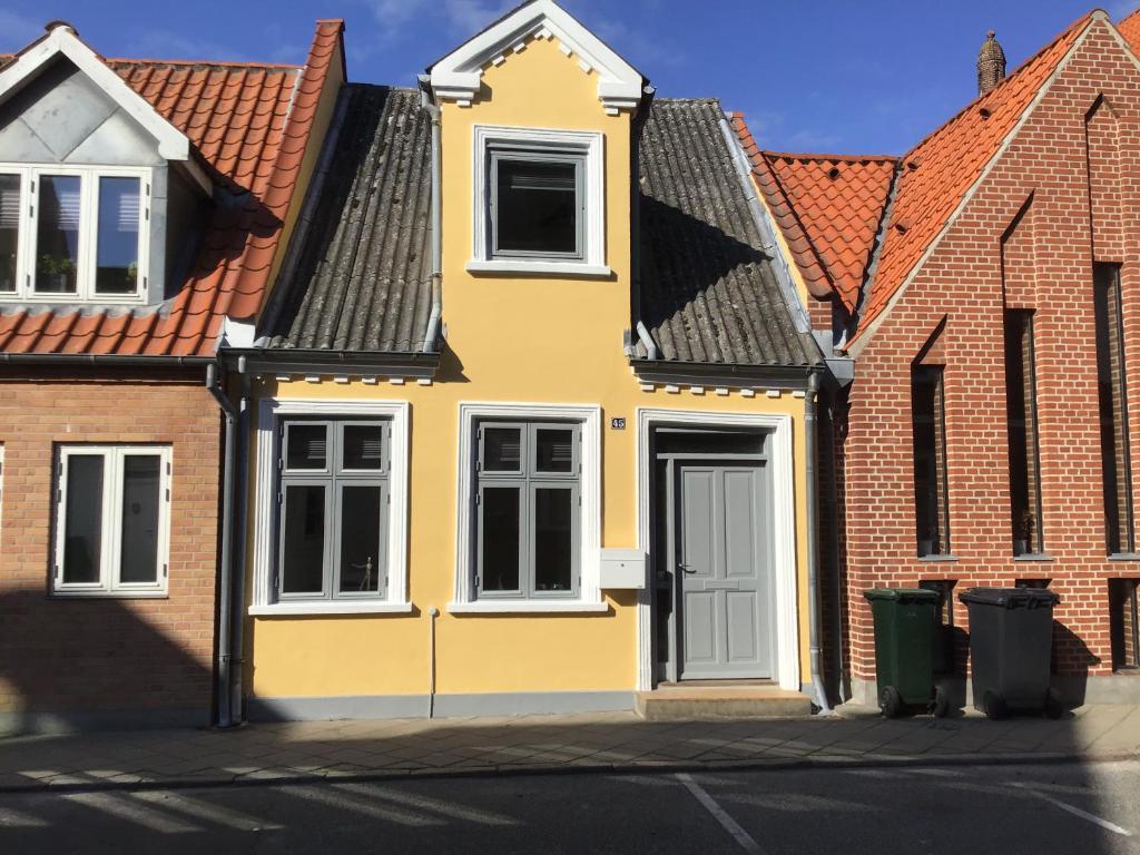 une maison jaune dans une rangée de maisons en briques dans l'établissement Nakskov Overnatning, à Nakskov