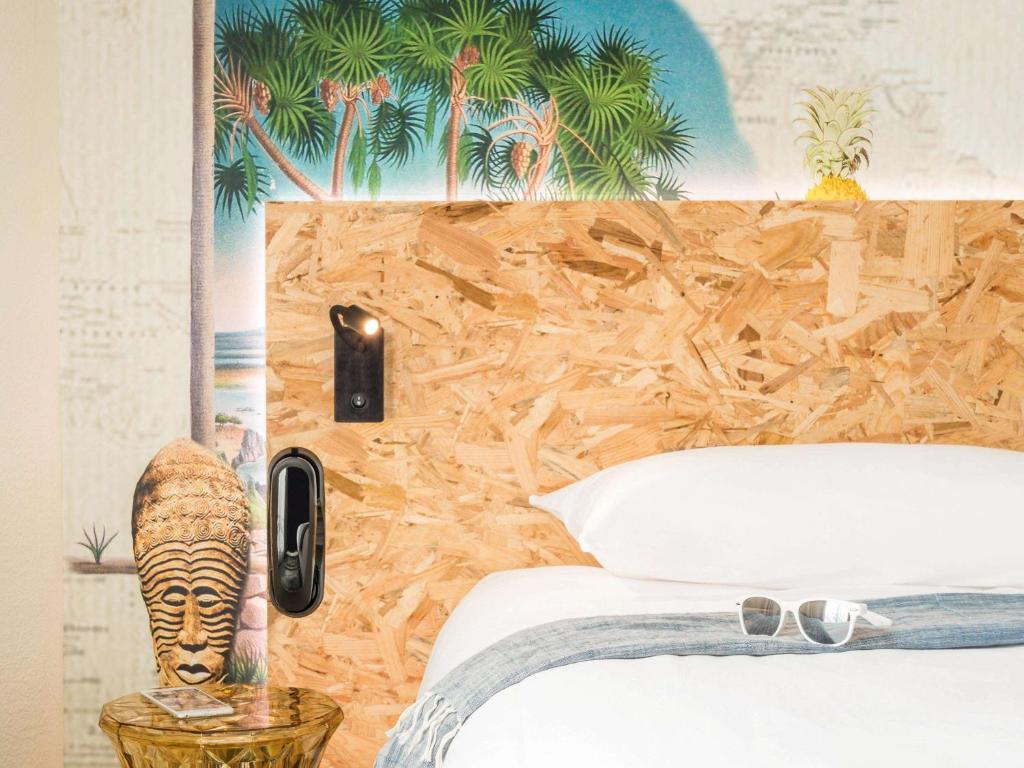 a bedroom with a bed with a mural of palm trees at ibis Styles Paris Boulogne Marcel Sembat in Boulogne-Billancourt