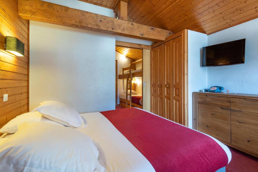 a bedroom with a bed and a tv on a wall at Hôtel Les Côtes, Résidence Loisirs et Chalets in Morzine