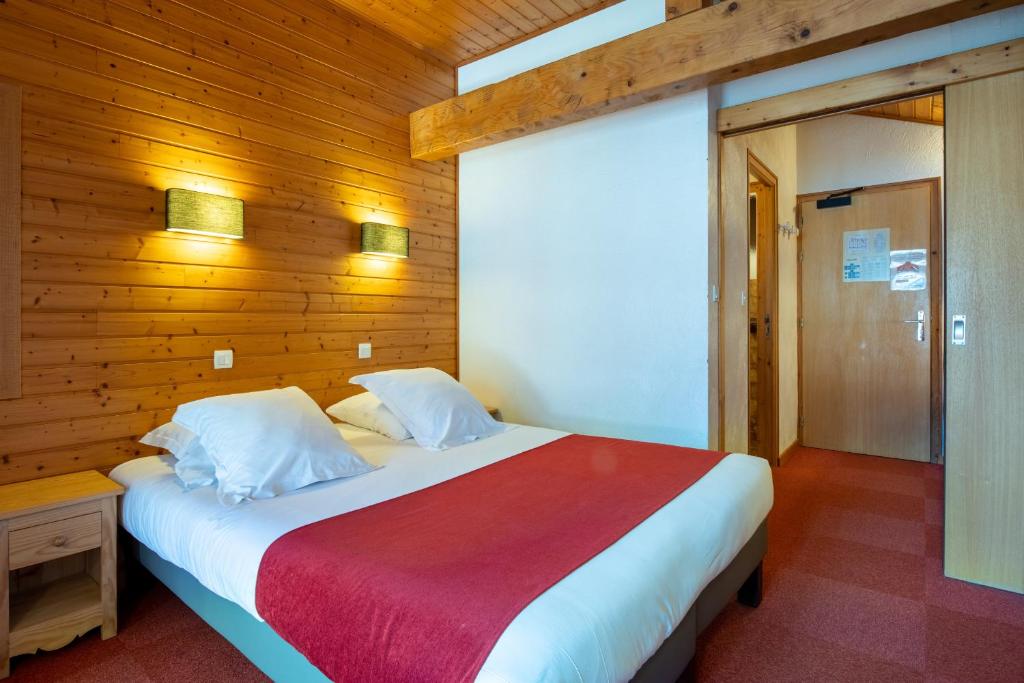 a bedroom with a large bed with a wooden wall at Hôtel Les Côtes, Résidence Loisirs et Chalets in Morzine