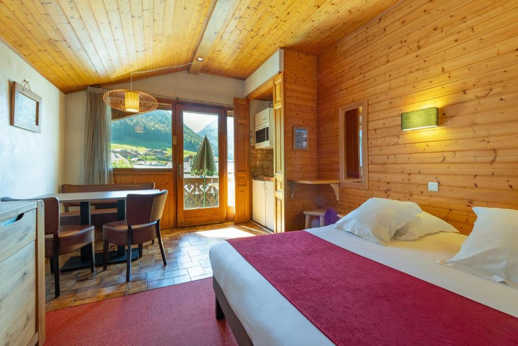 a bedroom with a bed and a dining room with a table at Hôtel Les Côtes, Résidence Loisirs et Chalets in Morzine