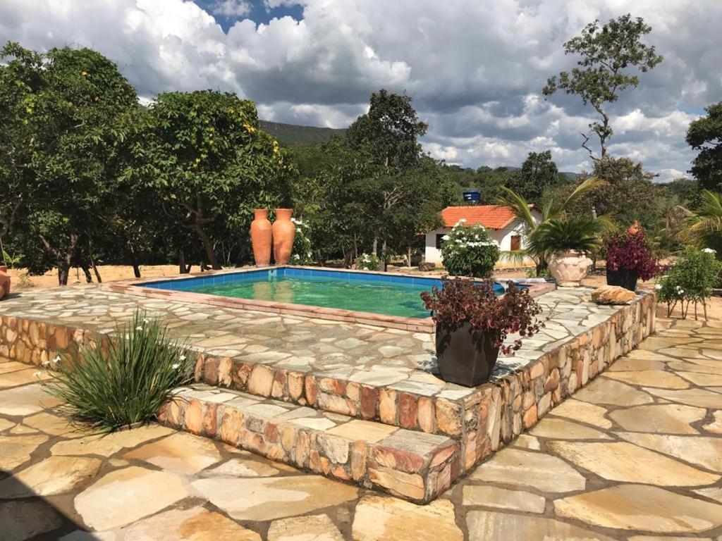 a swimming pool with a stone wall around it at Rancho do Paollo in Pirenópolis