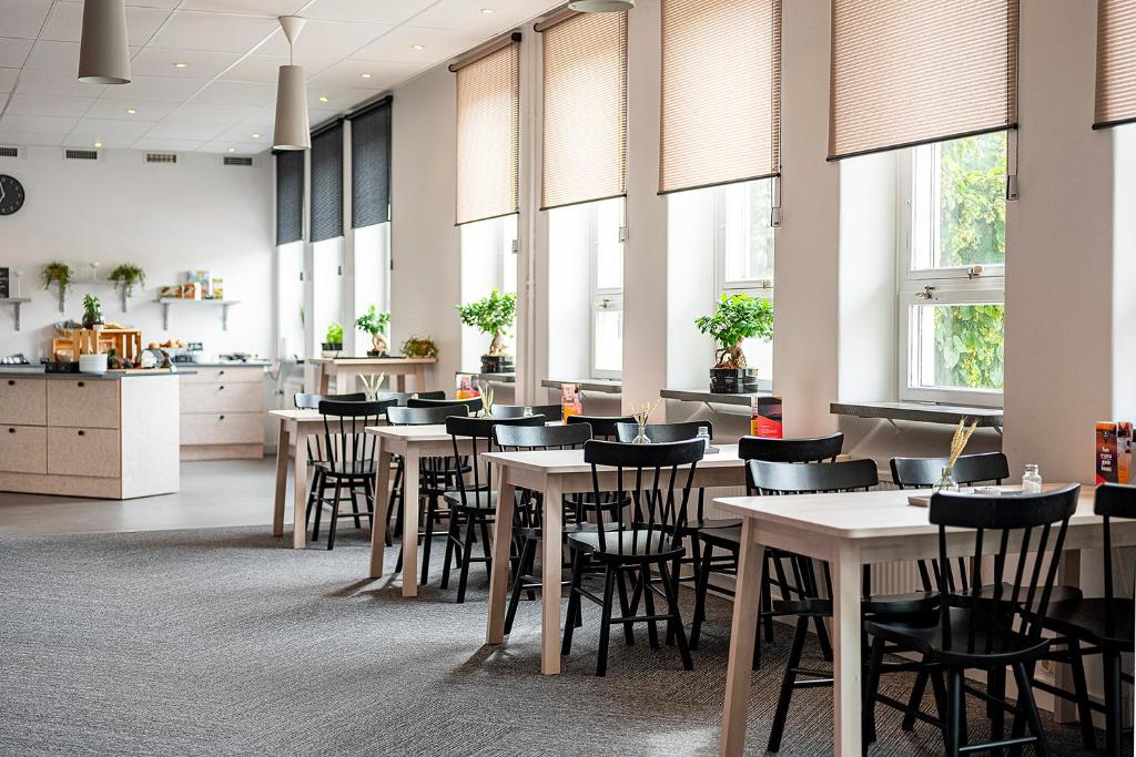 a restaurant with tables and chairs and windows at Norrland YMCA Hostel Umeå in Umeå