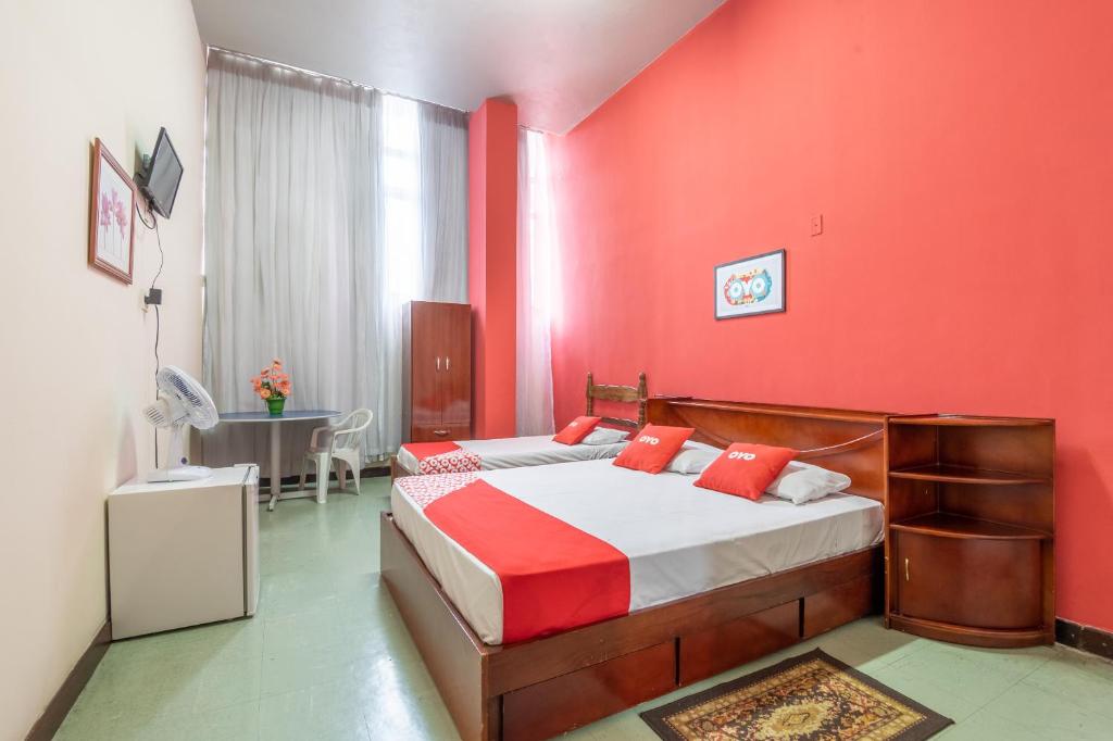 um quarto com paredes vermelhas e uma cama com almofadas vermelhas em OYO Hotel L'Espace - Jaraguá Belo Horizonte em Belo Horizonte