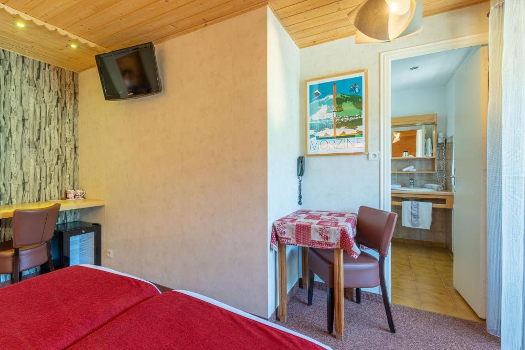 a bedroom with a table and chairs and a kitchen at Hôtel Les Côtes, Résidence Loisirs et Chalets in Morzine