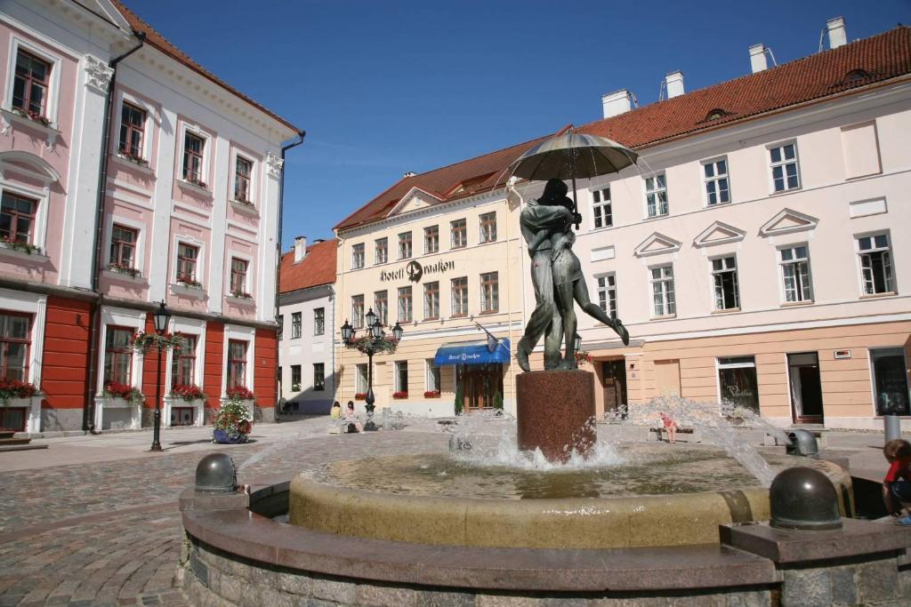 une statue d'une femme tenant un parapluie sur une fontaine dans l'établissement Draakon Hotel, à Tartu