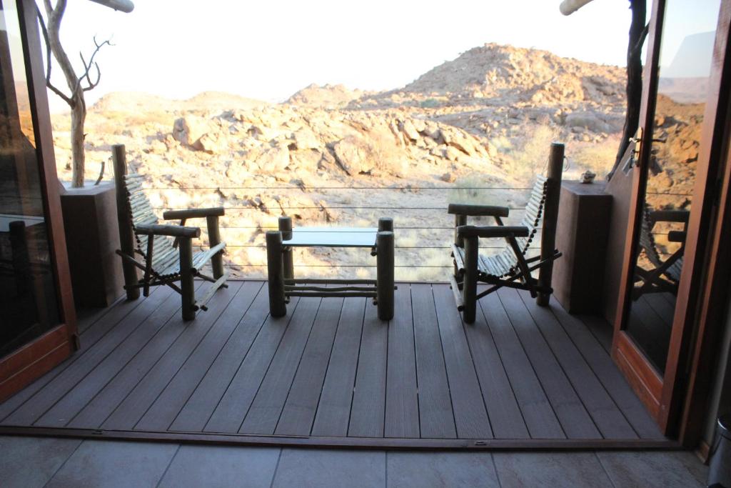 a porch with two chairs and a table and a view at Plato Lodge in Augrabies