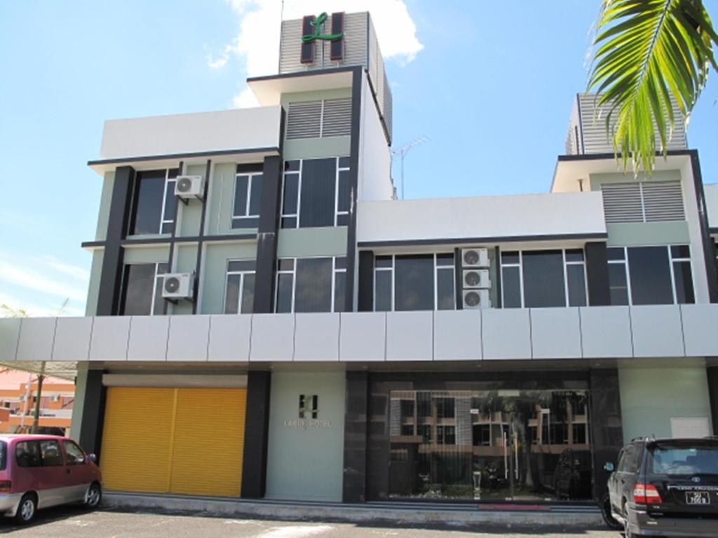 a building with cars parked in front of it at Labuk Hotel in Sandakan