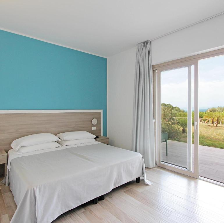 ein Schlafzimmer mit einem großen Bett und einem großen Fenster in der Unterkunft Costa degli Dei Resort in Capo Vaticano