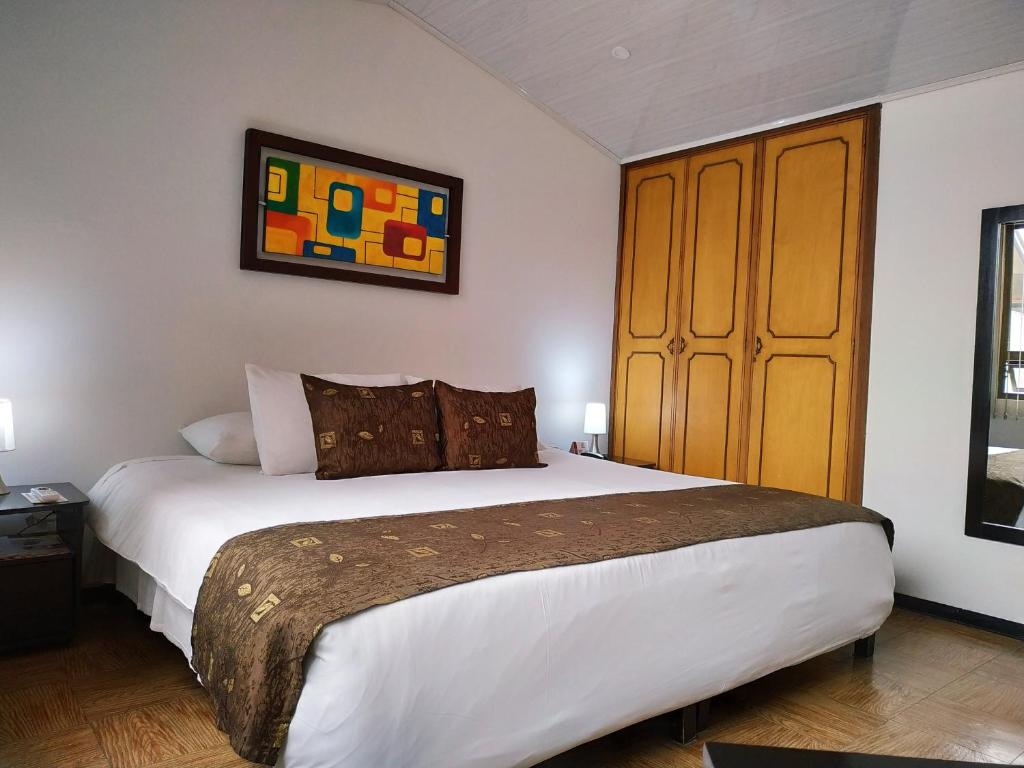 1 dormitorio con 1 cama grande y armario de madera en Hotel Confort Bogota, en Bogotá