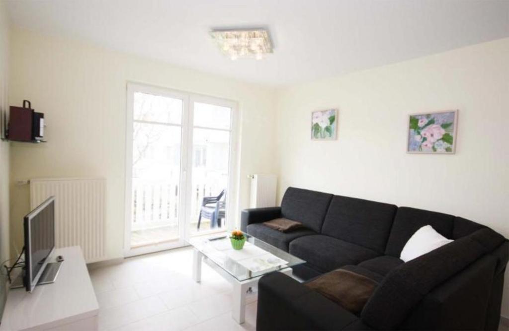 a living room with a black couch and a tv at Strandschloesschen-Haus-II-WE-11-9644 in Kühlungsborn