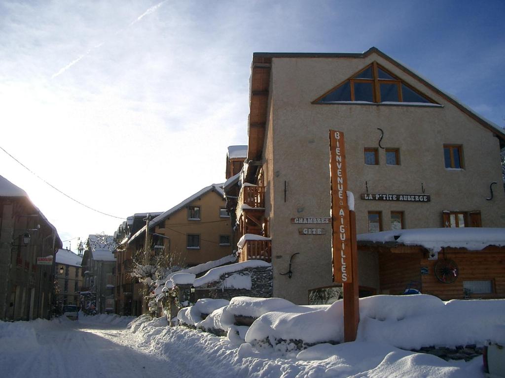 una calle cubierta de nieve frente a un edificio en La Ptite Auberge, en Aiguilles