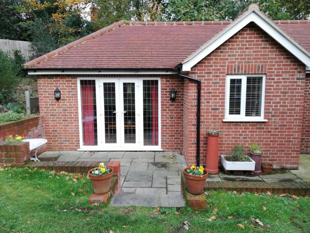 una pequeña casa de ladrillo con macetas en el patio en The Garden Room en Ipswich
