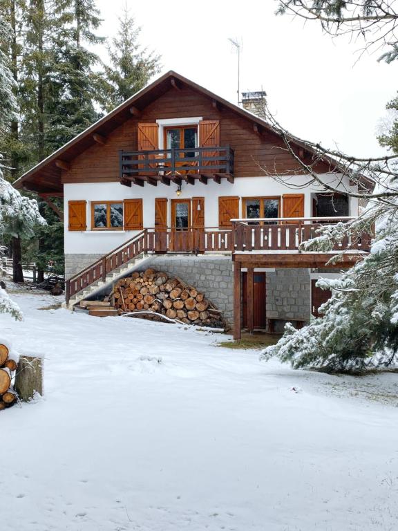 a house with a pile of logs in the snow at Chalet de l'Esquirol in Bolquere Pyrenees 2000