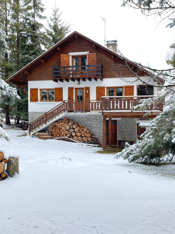 une maison avec un tas de bûches dans la neige dans l'établissement Chalet de l'Esquirol, à Bolquère-Pyrénées 2000
