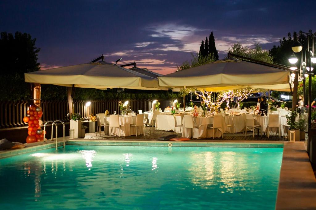 ein Pool mit Tischen und Sonnenschirmen in der Nacht in der Unterkunft Hotel Cristallo Relais, Sure Hotel Collection By Best Western in Tivoli