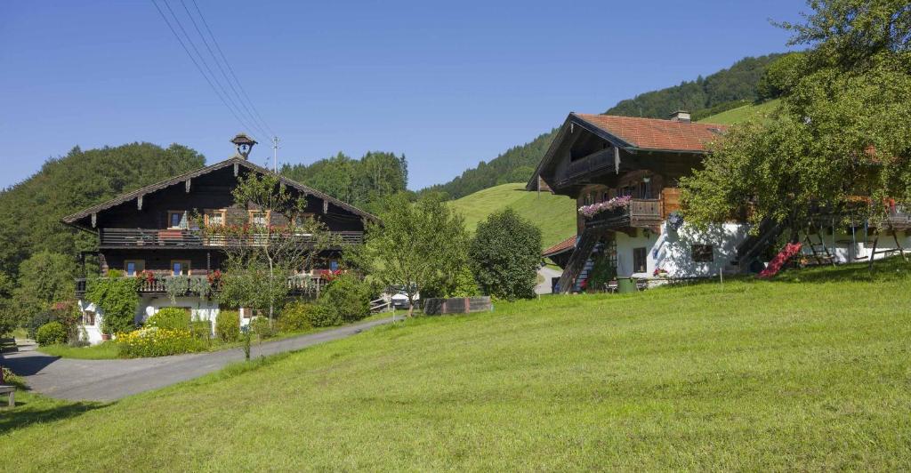een huis op een heuvel naast een grasveld bij Bergbauernhof Hinterseebach in Oberaudorf
