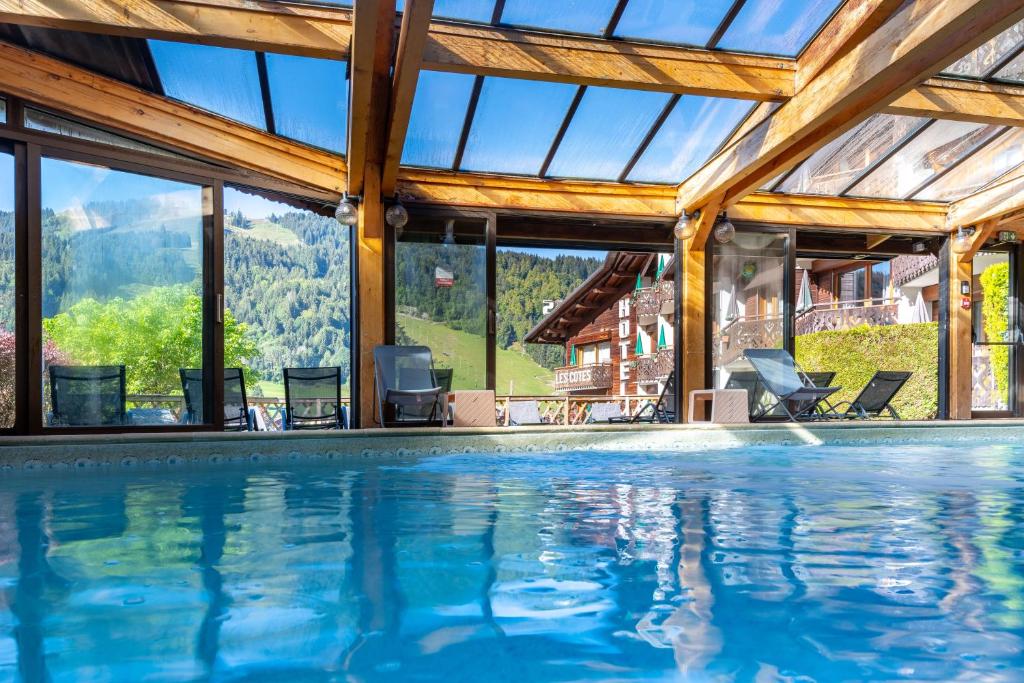 una piscina en una casa con vistas a las montañas en Hôtel Les Côtes, Résidence Loisirs et Chalets en Morzine