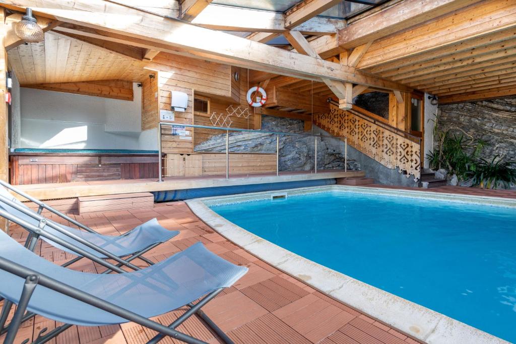 an indoor swimming pool with two chairs and a swimming pool at Hôtel Les Côtes, Résidence Loisirs et Chalets in Morzine