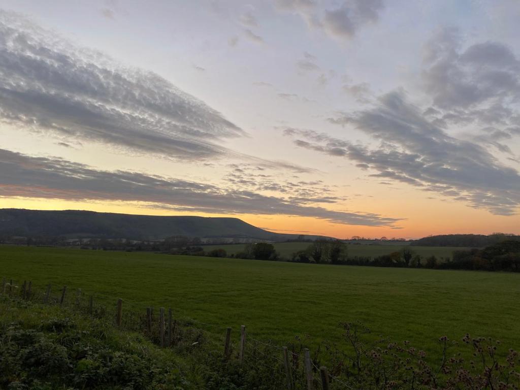 einen Sonnenuntergang über einem grünen Feld mit einem Zaun in der Unterkunft The Rose Cottage Inn in Selmeston