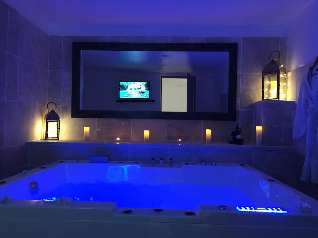 a bathroom with a large tub with a tv on the wall at Love Room Villa Charlene in Massoins