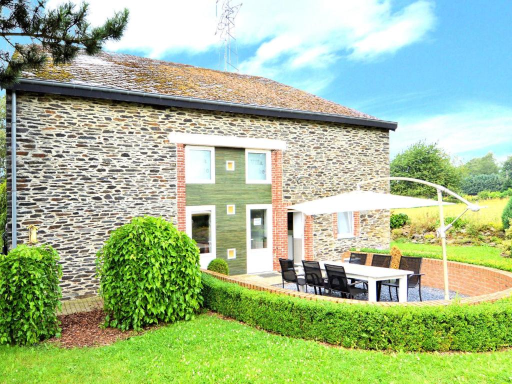 een stenen huis met een tafel en een paraplu bij Holiday home in La Roche en Ardennes with garden in La-Roche-en-Ardenne