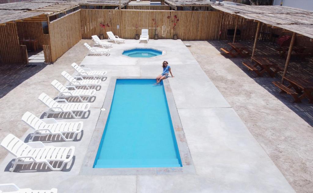 a woman is standing next to a swimming pool with chairs at Casa Caravanas in Paracas